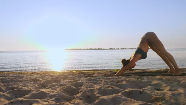 Bar antrenmanı. Açık havada uzanıyor. Yoga kumsalı. Atletik genç kadın gün batımında ya da gün doğumunda plajda minder üzerinde egzersiz yapıyor. Spor salonu açık havada. Fitness, bale, spor, yoga ve — Stok video