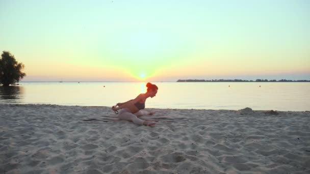 Растягивается на открытом воздухе. фитнес эластичный браслет. Атлетичная молодая женщина делает упражнения с помощью фитнес-эластичной ленты, на пляже во время заката или восхода солнца. Фитнес-тренировки на открытом воздухе. занятие спортом в — стоковое видео