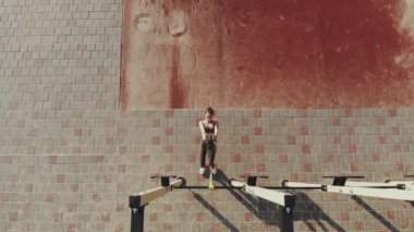 Açık havada egzersiz. Askı kayışları. Aero üst görünüm. Atletik genç kadın tüm vücut direnci egzersizlerini halka halatlarla yapıyor TRX, açık hava spor sahasında, spor salonunda. Spor salonu açık havada.