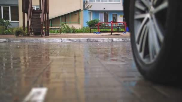 下雨了特写。雨滴落在潮湿的街道瓷砖上，衬托在操场上。外面下着雨，在住宅区的院子里。夏季淋浴. — 图库视频影像