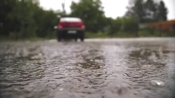 雨だ、水たまり。駐車場で雨が降ってる。接近中だ。雨滴は、暴風雨の間に水溜りに落ちます。夏のシャワー. — ストック動画