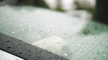Arabadaki yağmur damlaları. Yağmur. Yağmur yağıyor. Yağmur damlaları beyaz arabanın arka camına düşer ve yağmur yağarken yavaşça damlar. yakın plan