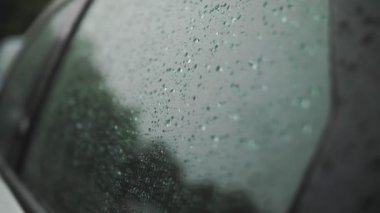 Arabadaki yağmur damlaları. Yağmur. Yağmur yağıyor. Yağmur damlaları yağmur sırasında modern arabanın yan cam yüzeyine düşer ve yavaşça aşağı süzülür. yakın plan
