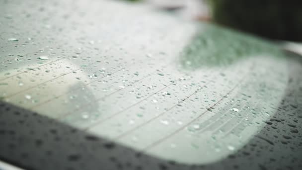 Gotas de lluvia en el coche. Lluvia. Llueve. las gotas de lluvia caen al parabrisas trasero del coche blanco y gotean lentamente, fluyendo hacia abajo, durante la lluvia. primer plano — Vídeos de Stock