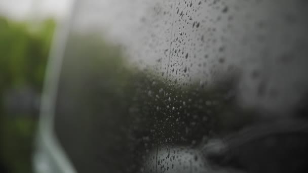 Gotas de lluvia en el coche. Lluvia. Llueve. gotas de lluvia caen y fluyen lentamente por la superficie de vidrio de la ventana lateral del coche moderno, durante la lluvia. primer plano — Vídeos de Stock
