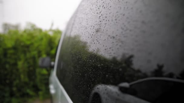 車の雨滴だ。雨だ。雨だ。雨が降るとゆっくりと近代的な車の側面窓ガラスの表面を流れる、雨の中。閉鎖 — ストック動画