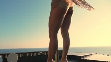 Direk dansı. uygun kadın jimnastikçi, bej mayosuyla, akrobatik egzersizler yapıyor metal döner direkte, gökdelen çatısında, muhteşem bir gündoğumu görüşü arka planında