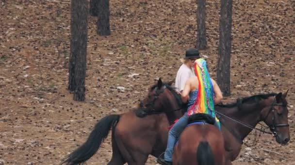 Lgbt. Regenbogen. Gleichgeschlechtliche Liebe. Ein junges gleichgeschlechtliches Paar lesbischer Frauen betreibt ein gemeinsames Hobby, das Reiten. Freundinnen reiten durch Wald und haben Spaß — Stockvideo