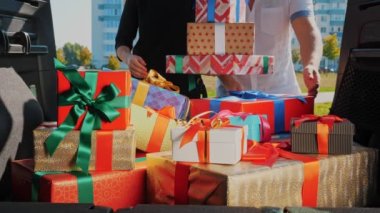 Teslimat. Bağış, bağış. Hediye kutuları arabada. Yakın plan. Kadın ve erkek, bagajdan güzelce paketlenmiş kutuları boşaltıyor. İçeriden görüntü. Noel hediyeleri. Çevrimiçi düzen.