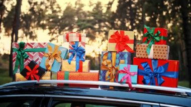 Hediye kutuları arabada. Teslimat. Bağış, bağış. Çok güzel paketlenmiş kutular, araba çatısı, güneş ışığı ve gün batımında uzanıyorlar. Yakın plan. Noel hediyeleri. Çevrimiçi düzen