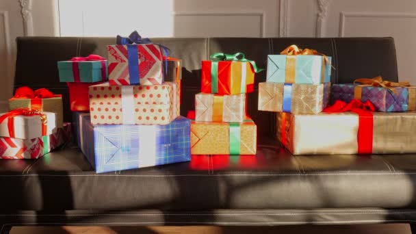 Divano con regali. Regali di Natale. Donazione, beneficenza. Ordine online. consegna. molti pacchi splendidamente avvolti, scatole, si trovano su un divano, sotto i raggi del sole. primo piano. lasso di tempo — Video Stock