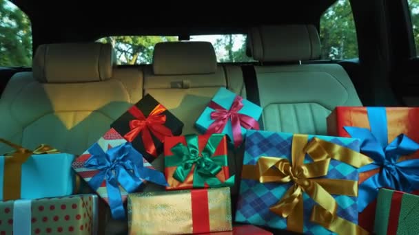 Geschenkboxen im Auto. Lieferung. Spende, Wohltätigkeit. viele schön verpackte Päckchen, Schachteln, liegen auf dem Rücksitz des Autos, in der Sonne. Nahaufnahme, Blick aus dem Inneren des Autos. Weihnachtsgeschenke. Online-Bestellung. — Stockvideo