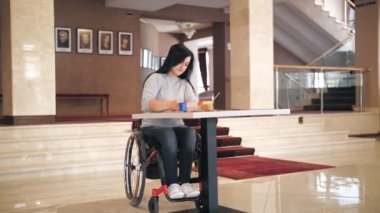 Tekerlekli. Maluliyet. Engelli genç kadın çizim yapıyor, masada tekerlekli sandalyede oturuyor. Engelliler için yaratıcı dersler. Eğitim, ilişki ve insanlık kavramı