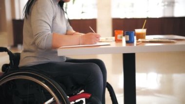 Tekerlekli. Maluliyet. Yakın plan. Engelli genç kadın resim çiziyor, tekerlekli sandalyede oturuyor. Engelliler için yaratıcı dersler. Eğitim, ilişki ve insanlık kavramı