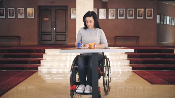 Wheelchair. disability. disabled young woman draws, sitting in a wheelchair at the table. creative lessons for people with disabilities. Education, relationship and humanity concept — Stock Video