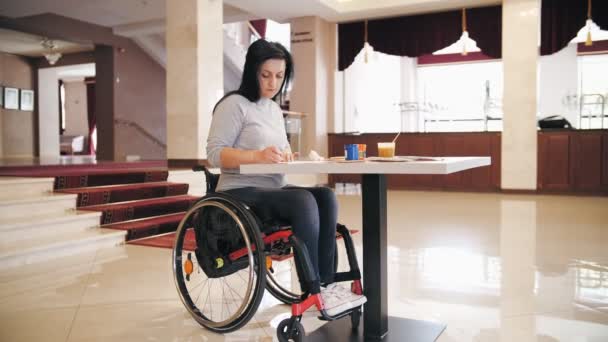 Fauteuil roulant. invalidité. jeune femme handicapée dessine des peintures, assise en fauteuil roulant à la table, seule. personne handicapée. Éducation, relation et concept d'humanité — Video