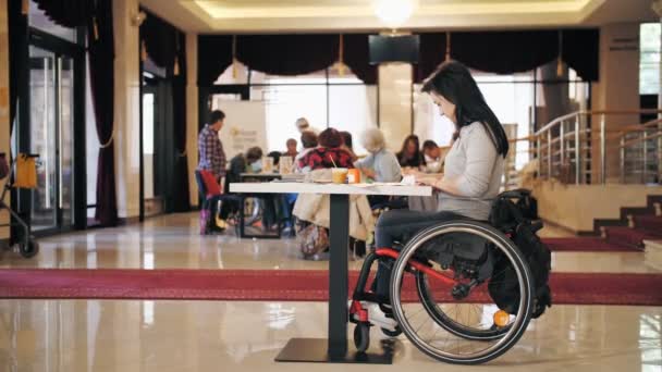 Wheelchair. disability. disabled young woman draws paints, sitting in wheelchair at table. creative group lessons for people with disabilities. Education, relationship and humanity concept — Stock Video