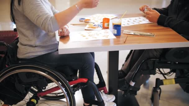 Tekerlekli. Maluliyet. Yakın plan. Engelli insanlar resim çiziyor, masadaki tekerlekli sandalyelerde oturuyorlar. Engelliler için yaratıcı grup dersleri. Eğitim, ilişki ve insanlık kavramı — Stok video