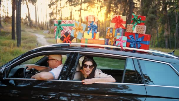 Cajas de regalo en el coche. Luna de miel. pareja en el amor divertirse dentro del coche, con muchos paquetes bellamente envueltos, cajas en el techo del coche, en los rayos del sol, al atardecer. entrega. Pedido en línea. regalos de aniversario — Vídeos de Stock