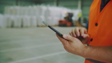 Tarım deposu. Depo. Yakın plan. Tabletli erkek eli. Girişim çalışanı, ambarda mısır tohumu ya da ayçiçeği taneciklerinin yüklenmesine karşı tablet üzerinde çalışır..