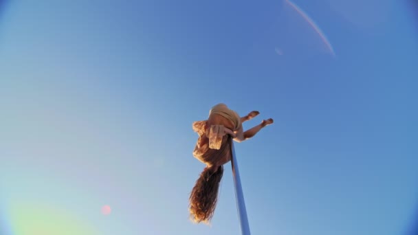 막대 춤. 암컷 체조 선수에게 적합 한 베지 레오타르트는, 푸른 하늘을 배경으로 금속으로 회전하는 장대 위에서 곡예를 한다. 아래에서 본 모습 — 비디오