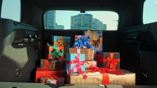 Подарочные коробки в машине. Служба доставки. много красиво обернутых посылок, коробок, лежат в багажнике машины, в солнечных лучах. крупный план, вид изнутри машины. пожертвования, благотворительность. Онлайн заказ. Рождественские подарки — стоковое видео