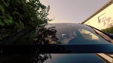 Aile gün batımında arabanın ön camından çekilmiş. Aile yolculuğunun mutlu anları otomobille.