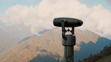 Dramatik beyaz bulutlara ve sisli dağ zirvelerine karşı turist dürbünlerinin silüeti.