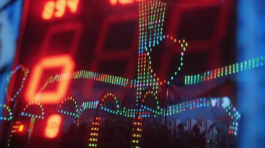 Elektronik skorbord, gece eğlence parkında sonuçlarla parıldıyor. Panayır alanında parlayan ışıklar.