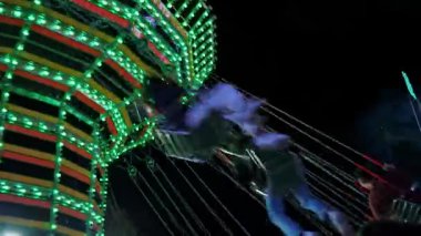 Aydınlatılmış zincir atlıkarınca Biella gece parkının arka planında hareket ediyor. Akşam keyfi ve eğlencesi için heyecan verici bir eğlence..