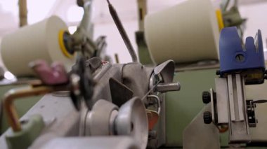 Tekstil fabrikasındaki iplik makaralarının yakın planıyla otomatikleştirilmiş dönen üretim hattı. Makineler devrede.