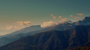 İtalyan Alpleri 'nde gün batımında hareket eden bulutlarla dramatik dağ zirveleri. Karlı tepeler ve mavi gökyüzü içeren yüksek irtifa kış manzarası.