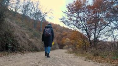 İtalya 'nın altın sonbahar dağlarında huzurlu bir patikada yürüyen bir yürüyüşçünün arka görüntüsü.