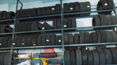 Tamir merkezindeki raflarda duran sıra sıra araba lastikleri. Tekerlek lastiği yığını kurulum için hazır.