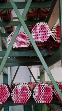 Yeşil fabrika raflarında kırmızı uçlu bakır boruların dikey görüntüsü. Metal işçiliği envanteri.