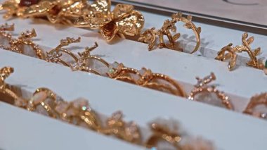 Mağaza vitrininde ince detaylarla altın yüzüklerin çeşitliliği. Lüks alışveriş ve mücevher seçimi kavramı.