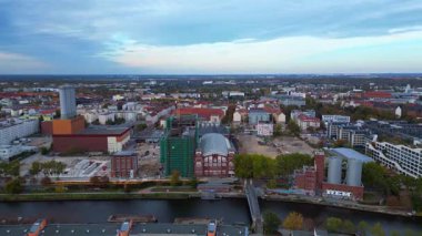 Spree Nehri 'nin kıyısındaki şehir merkezinde çalışan birleşik ısı ve elektrik santrali ve inşaat halindeki yeni binalar. Hız rampası hiper hareket zamanı hızlandırılmış panorama yörünge dronu 