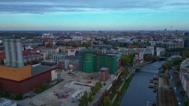 Spree Nehri 'nin kıyısındaki şehir merkezinde çalışan birleşik ısı ve elektrik santrali ve inşaat halindeki yeni binalar. geniş yörünge görünümü dronu 