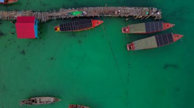 Güneydoğu Asya 'da bir körfezde, bungalovları, rıhtımları ve ahşap tekneleri olan Koh Rong adası köyü. Üstten kumandalı hava aracı kameraları aşağıya bakıyor. 