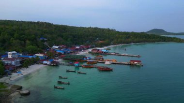 Güneydoğu Asya 'da bir körfezde, bungalovları, rıhtımları ve ahşap tekneleri olan Koh Rong adası köyü. rotasyon pan 'dan sağ drona 