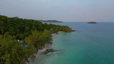 Koh Rong adasındaki tropik plajda turkuaz su ve yoğun yeşil orman bulunuyor. İHA panorama genel görüntüsü alçalıyor 