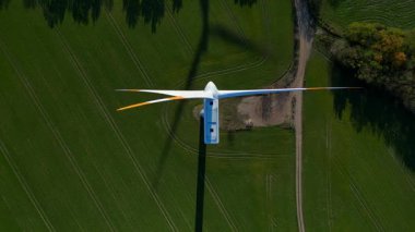 Sonbahar Almanya 'sında otobanın yanındaki yeşil alanda duran rüzgar türbini gölgesi yenilenebilir enerji üretiyor. dikey kuş bakışı dron 
