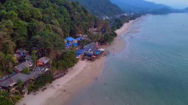 Koh Chang adasındaki beyaz kum plajı, turkuaz deniz kıyısındaki yeşil dağ ormanı. İHA alçalıyor 