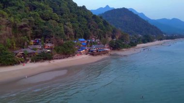 Koh Chang adasındaki beyaz kum plajı, turkuaz deniz kıyısındaki yeşil dağ ormanı. Ters İHA uçuşu 