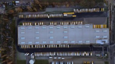 Yükleme rıhtımlarına park etmiş çok sayıda kamyonu olan büyük bir depo tesisi, küresel dağıtımı temsil ediyor. dikey kuşların bakış açısı İHA 'dan iniyor 