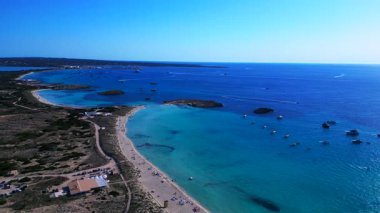 Açık turkuaz suyu ve mavi gökyüzünün altında demirli teknelerle dolu bir sahil şeridi. panorama genel görünüm dronu 