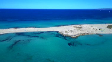 Platja de ses Illetes 'in açık turkuaz okyanuslu plaj formenterasını ve açık bir gökyüzü altında dinlenen insanları gösteren hava manzarası. rotasyon pan 'dan sağ drona 