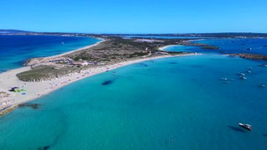 Platja de ses Illetes 'in açık turkuaz okyanuslu plaj formenterasını ve açık bir gökyüzü altında dinlenen insanları gösteren hava manzarası. panorama yörünge dronu 