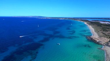 Açık turkuaz suyu ve mavi gökyüzünün altında demirli teknelerle dolu bir sahil şeridi. panorama genel görünüm dronu 