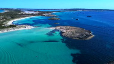 Balear Adaları 'ndaki kumlu bir sahil şeridi yakınlarında kristal berrak sularda yüzen sayısız lüks yat ve tekne. En iyi hava görüntüsü hız rampası hiper hareket süresi hızlandırma ters uçan drone 